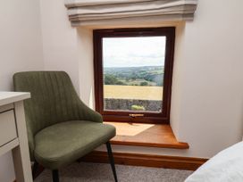 A bedroom with a chair and a view at Swallow Cottage in Lealholm