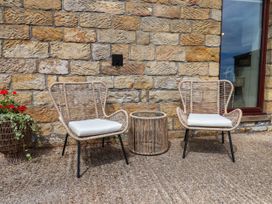 Two chairs and a table in front of a stone wall at Swallow Cottage Lealholm