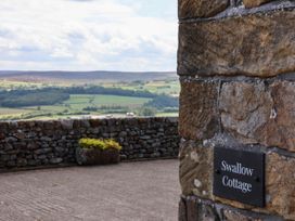 A stone wall with a sign for Swallow Cottage at Lealholm