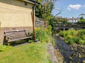 A garden area with a wooden bench and flowers beside a stream at Bobbin Nook