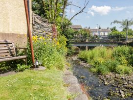 A garden area with a bench and a stream near a bridge at Bobbin Nook
