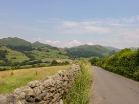 A road beside a stone wall with hills in the background at Bobbin Nook