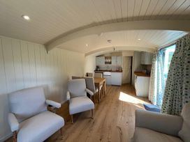 A living room with chairs and a kitchen area at The Orchard in Ringstead