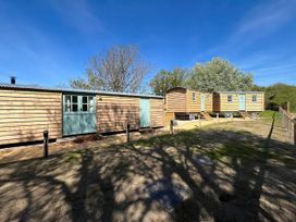Outdoor area with wooden cabins and trees at The Orchard in Ringstead