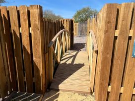 A wooden bridge over a pathway enclosed by a wooden fence at The Orchard in Ringstead