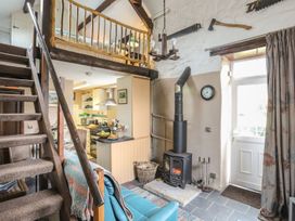 A living room with a sofa and wood stove at Ty Gwenno in Criccieth