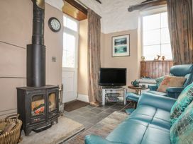 A living room with a stove and television at Ty Gwenno in Criccieth