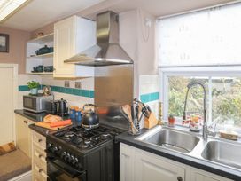 A kitchen with an oven, sink, and microwave at Ty Gwenno in Criccieth
