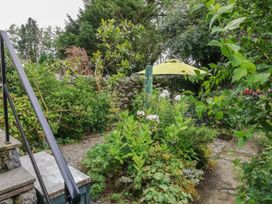A garden with a stone path and a green umbrella at Ty Gwenno in Criccieth