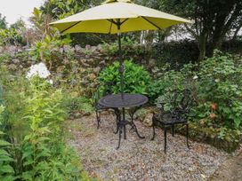 A garden with a table, chair, and umbrella at Ty Gwenno in Criccieth