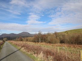 A road with grass and trees alongside in a mountainous area at Ty Gwenno in Criccieth