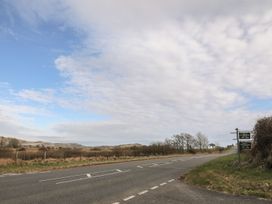 A road with a signpost and fields in the background at Ty Gwenno Criccieth