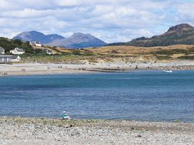 A beach scene with water and mountains at Ty Gwenno in Criccieth