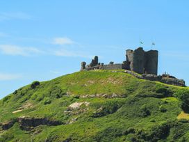 A castle on a hill with flags at Ty Gwenno in Criccieth