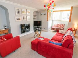 A living room with a red sofa and armchairs and a television at The Hideaway in Whitby
