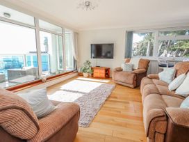 A living room with a sofa, armchairs, television, and large windows at Flat 17 Golden Gates in Poole