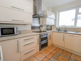 A kitchen with cabinets, stove, microwave, and sink at Flat 17 Golden Gates in Poole