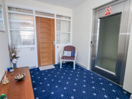 A hallway with a chair and elevator at Flat 17 Golden Gates Poole