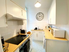 A kitchen with a clock, sink, and appliances at 2A Redcliffe in Torquay