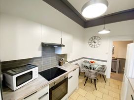 A kitchen with a microwave, oven, and dining table at 2B Redcliffe in Torquay