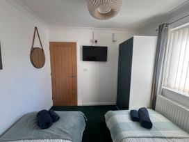 A bedroom with two beds, a wardrobe, and a television at Seaview in Pakefield