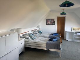 A bedroom with two beds, a dresser, and a nightstand at Seaview in Pakefield