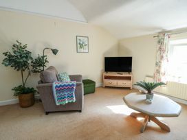 A living room with an armchair and television at Castle Gardens Apartment Beaumaris
