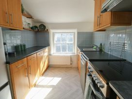 A kitchen with cabinets and a window at Castle Gardens Apartment Beaumaris