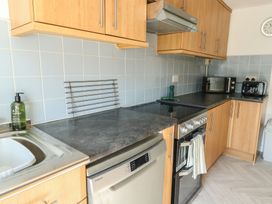 A kitchen with appliances and cabinets at Castle Gardens Apartment in Beaumaris