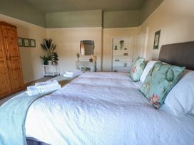 A bedroom with a bed and wooden wardrobe at Castle Gardens Apartment in Beaumaris