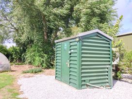 A green shed in a garden with gravel path at The Damselfly