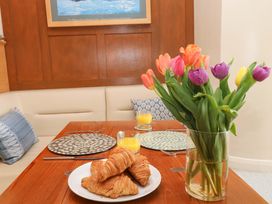 A dining room table with croissants and a vase of flowers at 24 The Salcombe, Salcombe