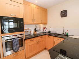 A kitchen with cabinets, oven, microwave, sink, and clock at 24 The Salcombe in Salcombe