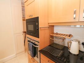 A kitchen with an oven, microwave, kettle, and dish rack at 24 The Salcombe, Salcombe