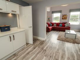A kitchen area leading to a living room with a red sofa at Sugar Loft in Silloth