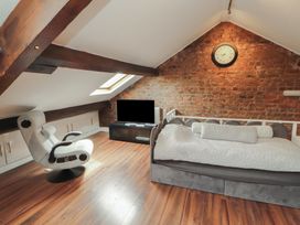 An attic room with a bed, chair, and television at Sugar Loft in Silloth