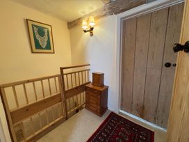 A hallway with a wooden door and chest of drawers at Cutbush Farmhouse in Norwich