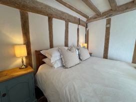 A bedroom with a bed and side table at Cutbush Farmhouse in Norwich