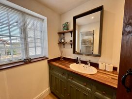 A bathroom with a sink, mirror, and shelf at Cutbush Farmhouse in Norwich