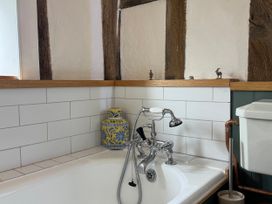 A bathroom with a bathtub and sink faucet at Cutbush Farmhouse Norwich