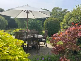 A garden with a table and chairs under an umbrella at Cutbush Farmhouse in Norwich