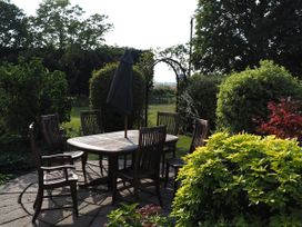 A garden with a wooden table and chairs at Cutbush Farmhouse Norwich