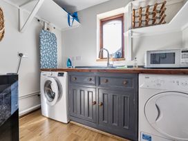 A laundry room with a washing machine, dryer, and kitchen sink at Cutbush Farmhouse Hingham