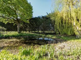 A garden with trees and a pond at Cutbush Farmhouse in Hingham