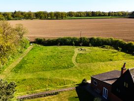 A garden with a house and surrounding fields at Cutbush Farmhouse in Hingham
