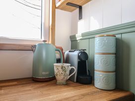 A kitchen counter with a kettle, cup, coffee machine, and storage containers at Salt Haven Shepards Hut Pevensey