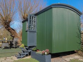 A green shepherd's hut with outdoor seating area at Salt Haven Shepards Hut Pevensey
