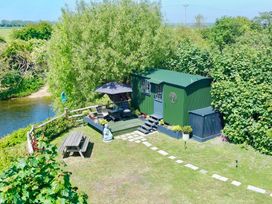 A garden with a shepherd's hut, seating area, and plants at Salthaven Shepherds Hut Pevensey Bay
