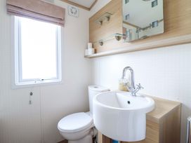 A bathroom featuring a sink, toilet, and mirror at Pemberton Knightsbridge in Morfa Bychan