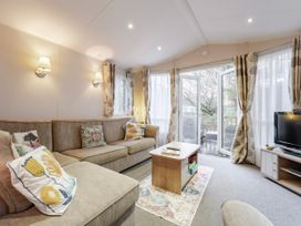 A living room with a sofa, television, and table at Sprindrift - Kelling Heath Holiday Park, Holt